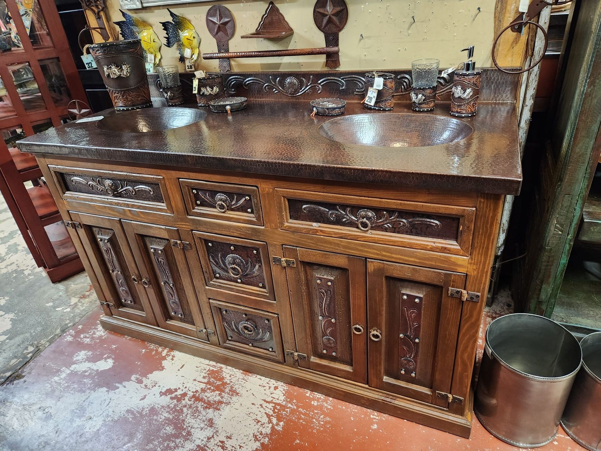 Wooden bathroom vanity with copper countertop and sinks, carved details, and rustic aesthetic.