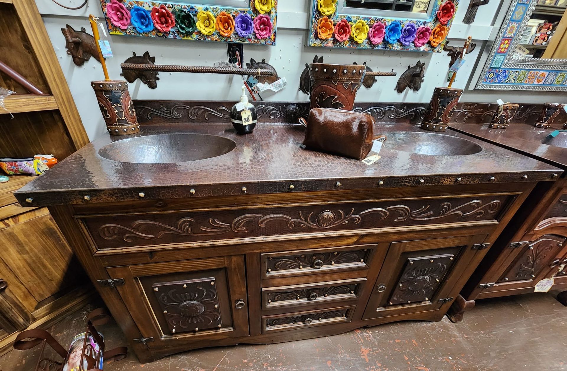 Double bathroom vanity with copper sinks and ornate wooden cabinetry, decorative metal accents.