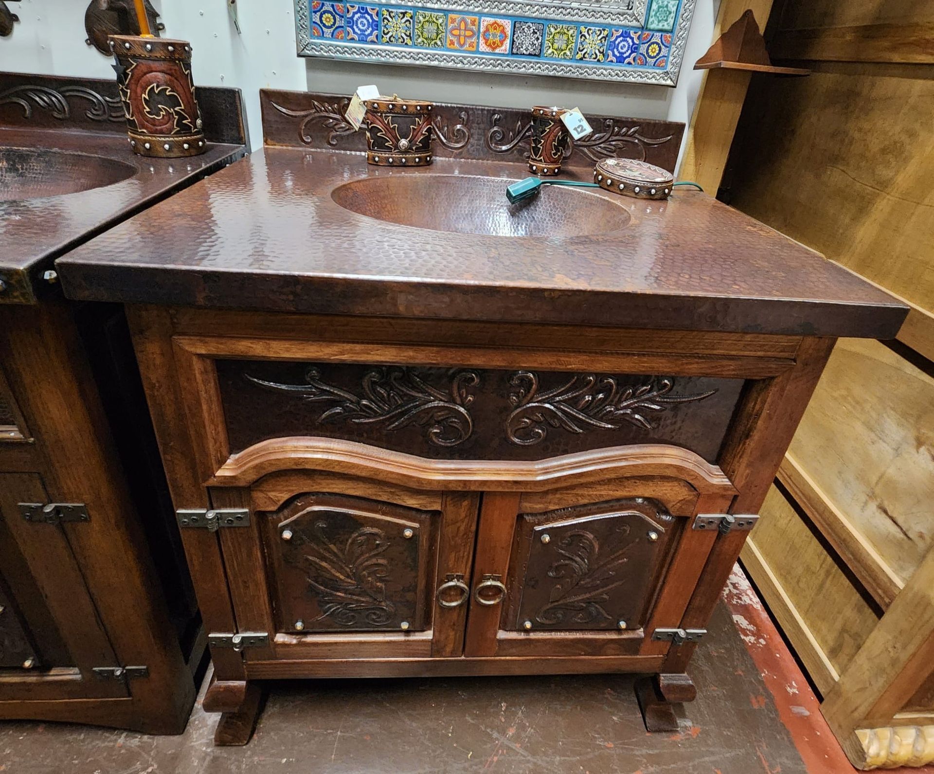 Wooden vanity with a copper sink, intricate detailing, and floral carvings. The warm tones create a rustic aesthetic.