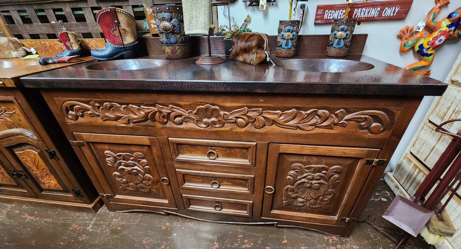 Wooden vanity with two copper sinks, elaborate carvings on the doors and drawers.