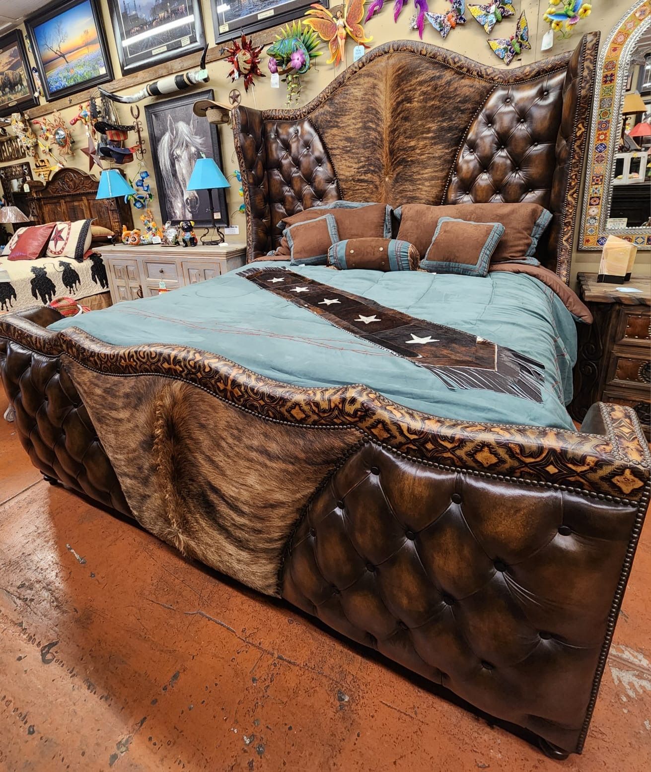 Luxurious western-style bed with a high, button-tufted headboard and cowhide accents. The room has wooden floors and various decorative items.