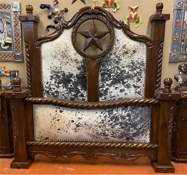 Western-style bed with dark wood frame, cowhide upholstery, and a large wooden star.