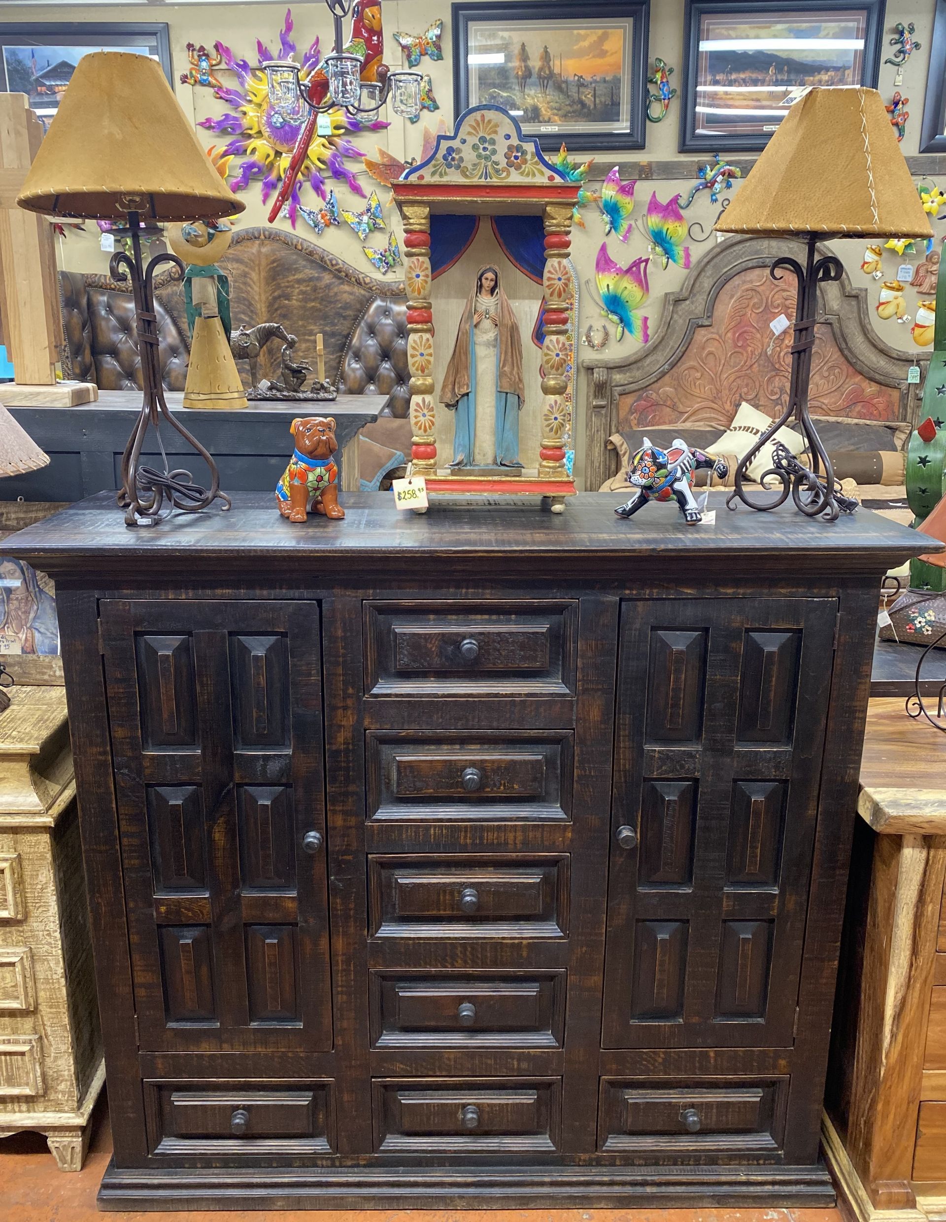 Dark wooden cabinet with lamps, and decorative items displayed on top in a shop setting.