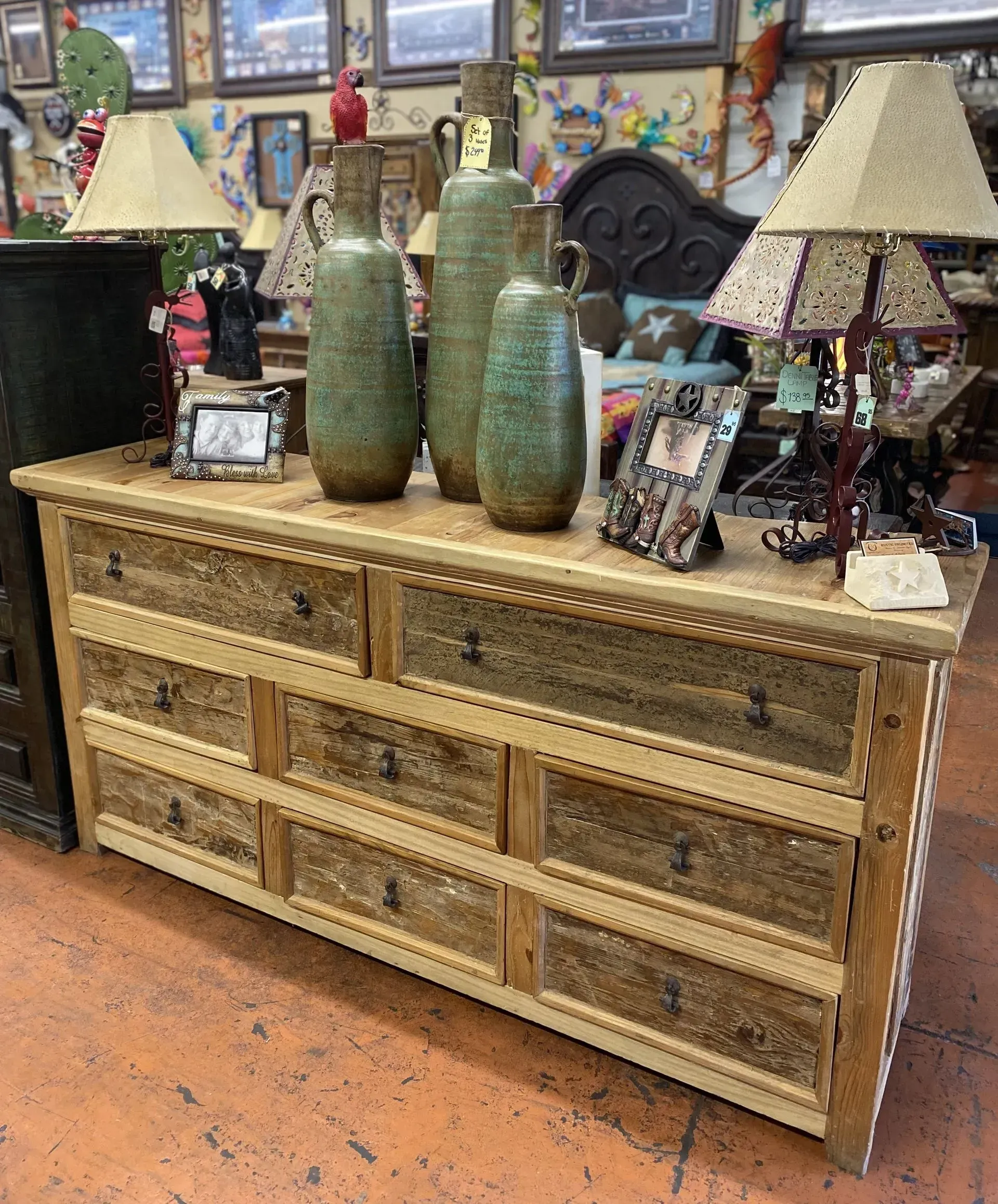 A rustic wooden dresser with several drawers and a collection of vases and lamps on top.