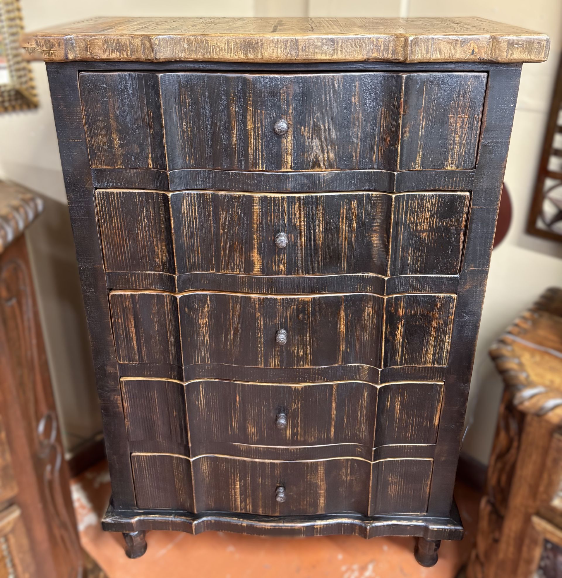 Dark wooden chest with four drawers and a decorative, light-colored top. The chest has a distressed finish and small knobs.