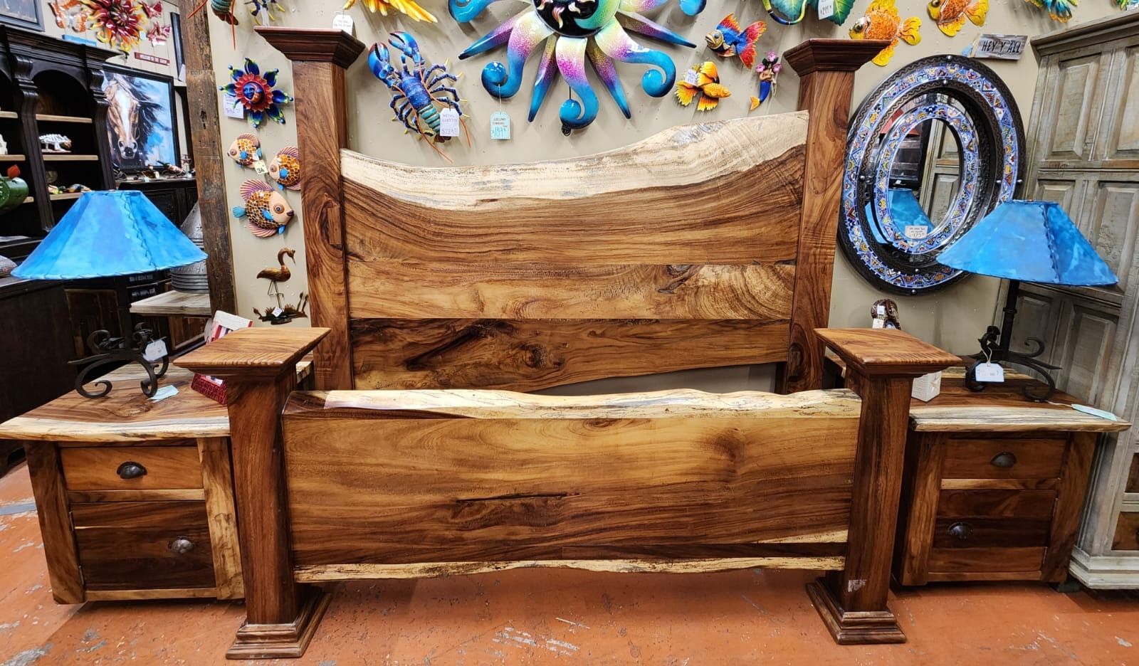 Rustic wooden bed frame with matching nightstands in a shop, decorated with colorful art.