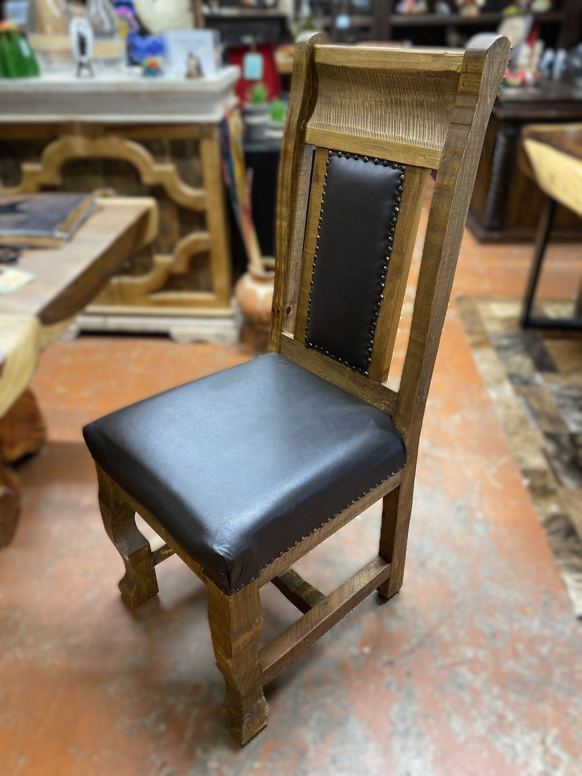 Wooden chair with dark brown leather seat and back, in a room with wood furniture.