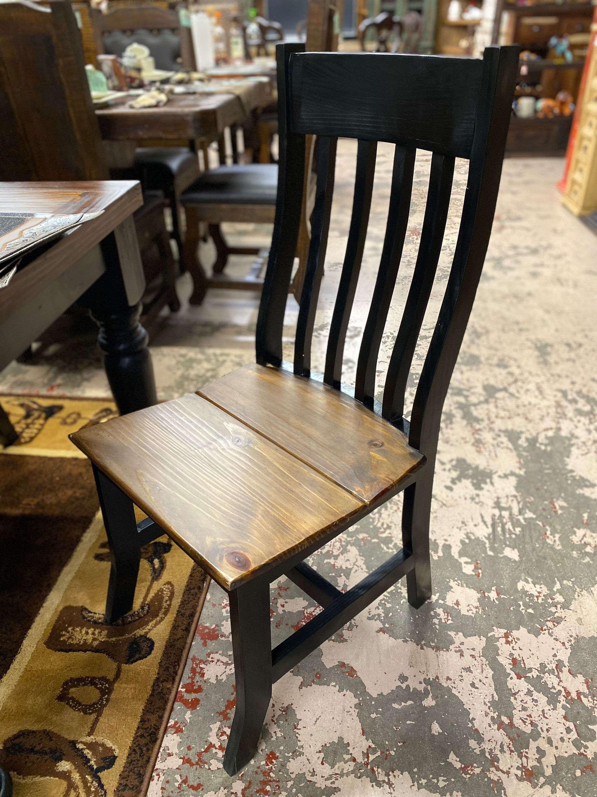 Wooden dining chair with a dark painted frame and a natural-toned seat and back slats.