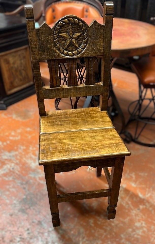 Wooden chair with a Texas star carved into the backrest, set on an orange floor.
