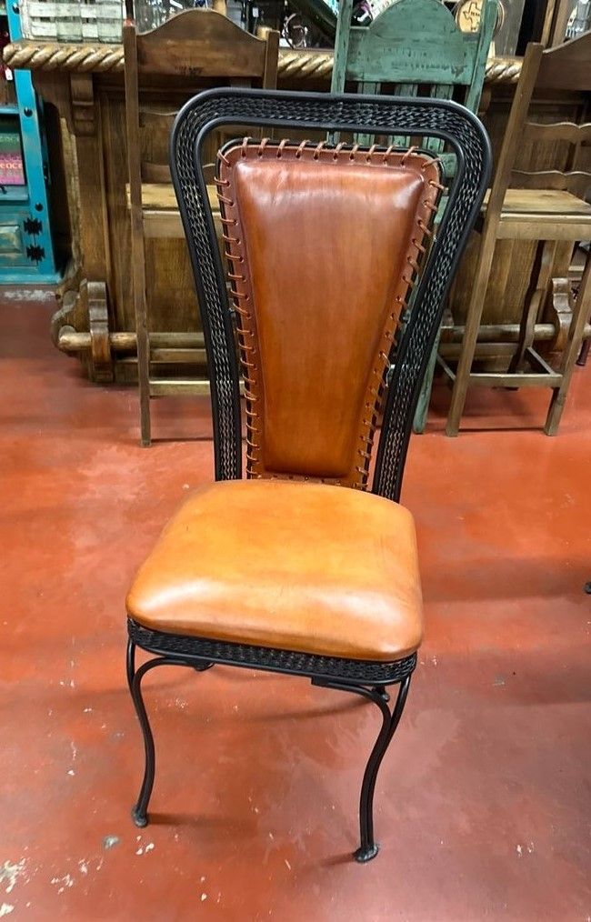 Leather and wrought iron dining chair with a brown seat and back, set on a red floor.
