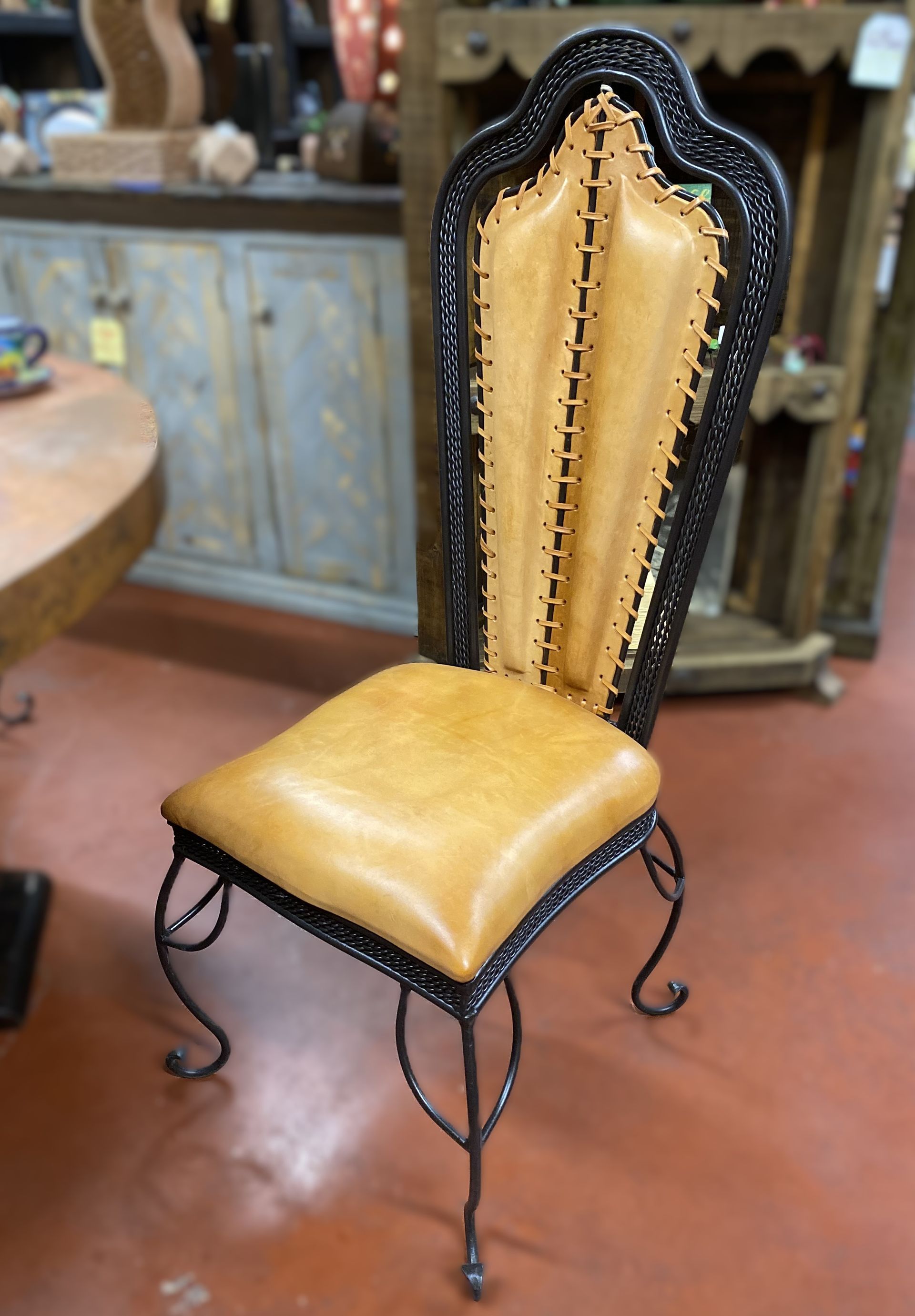 Tan leather and black wrought iron chair in a store setting.
