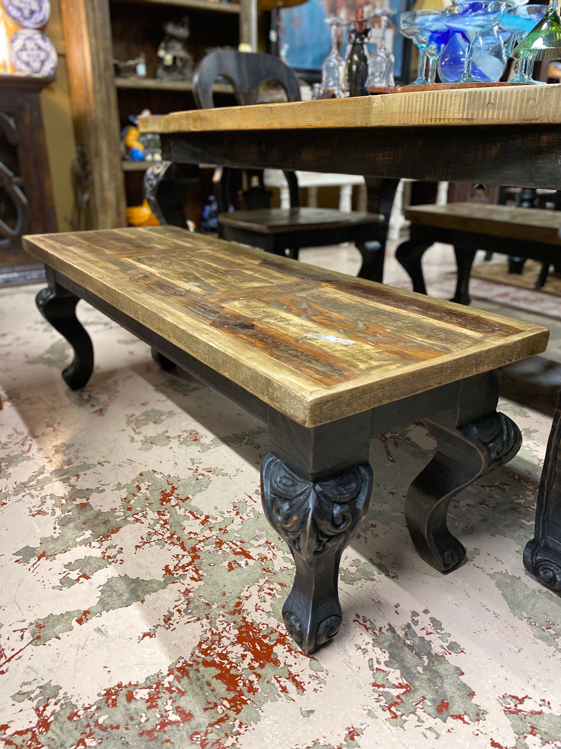 Low wooden rectangular table with ornate dark legs and a distressed wood top.