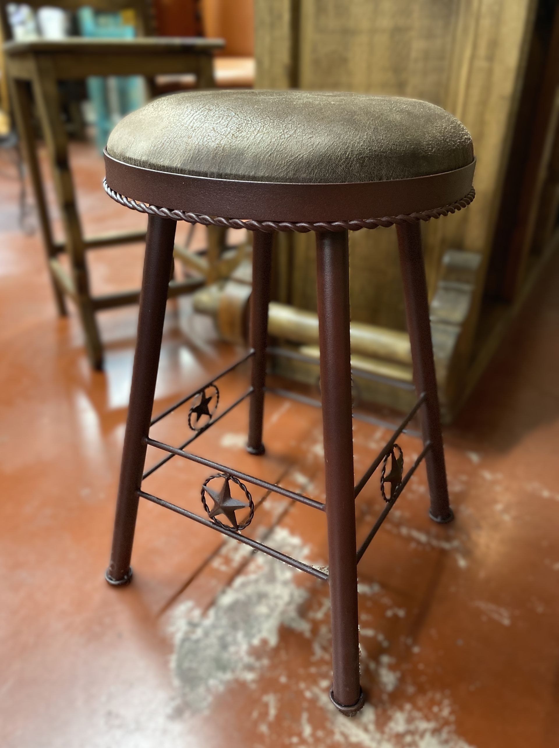 Brown and gold barstool with a circular seat, metal legs, and star accents.