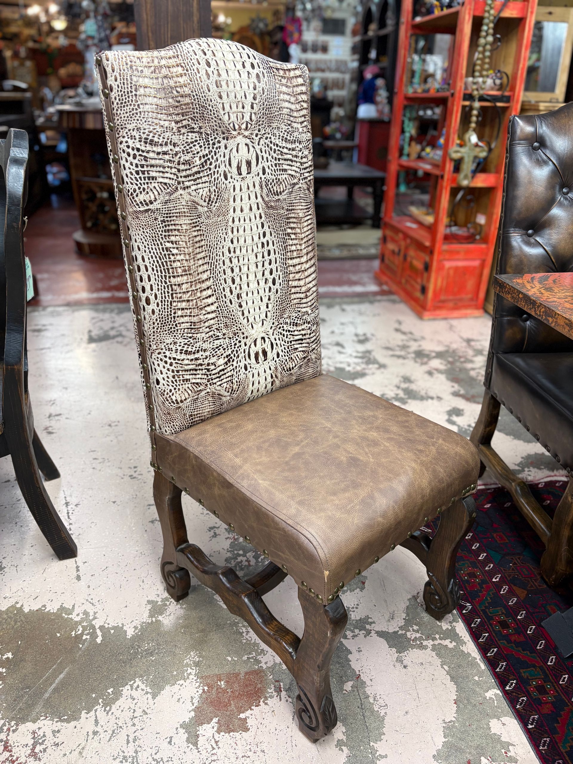 A decorative dining chair with an animal print back and brown leather seat, set in a shop with furniture and objects.