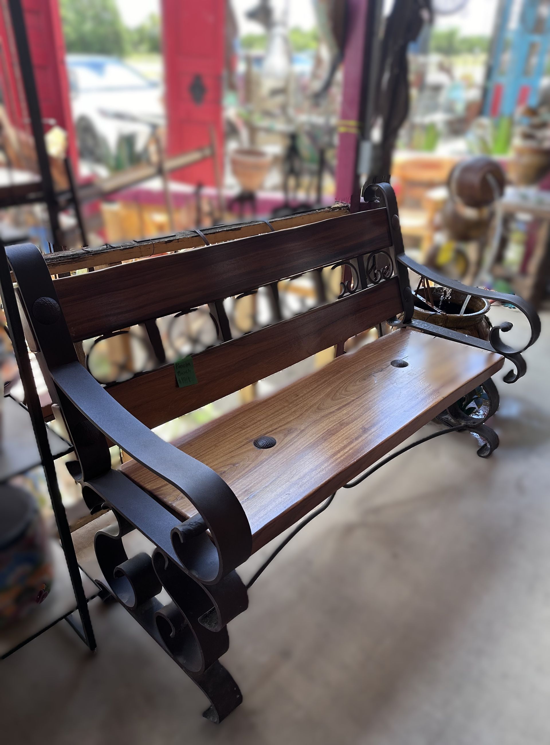 Wooden bench with black iron frame, outdoors. The bench has a dark brown seat and backrest.