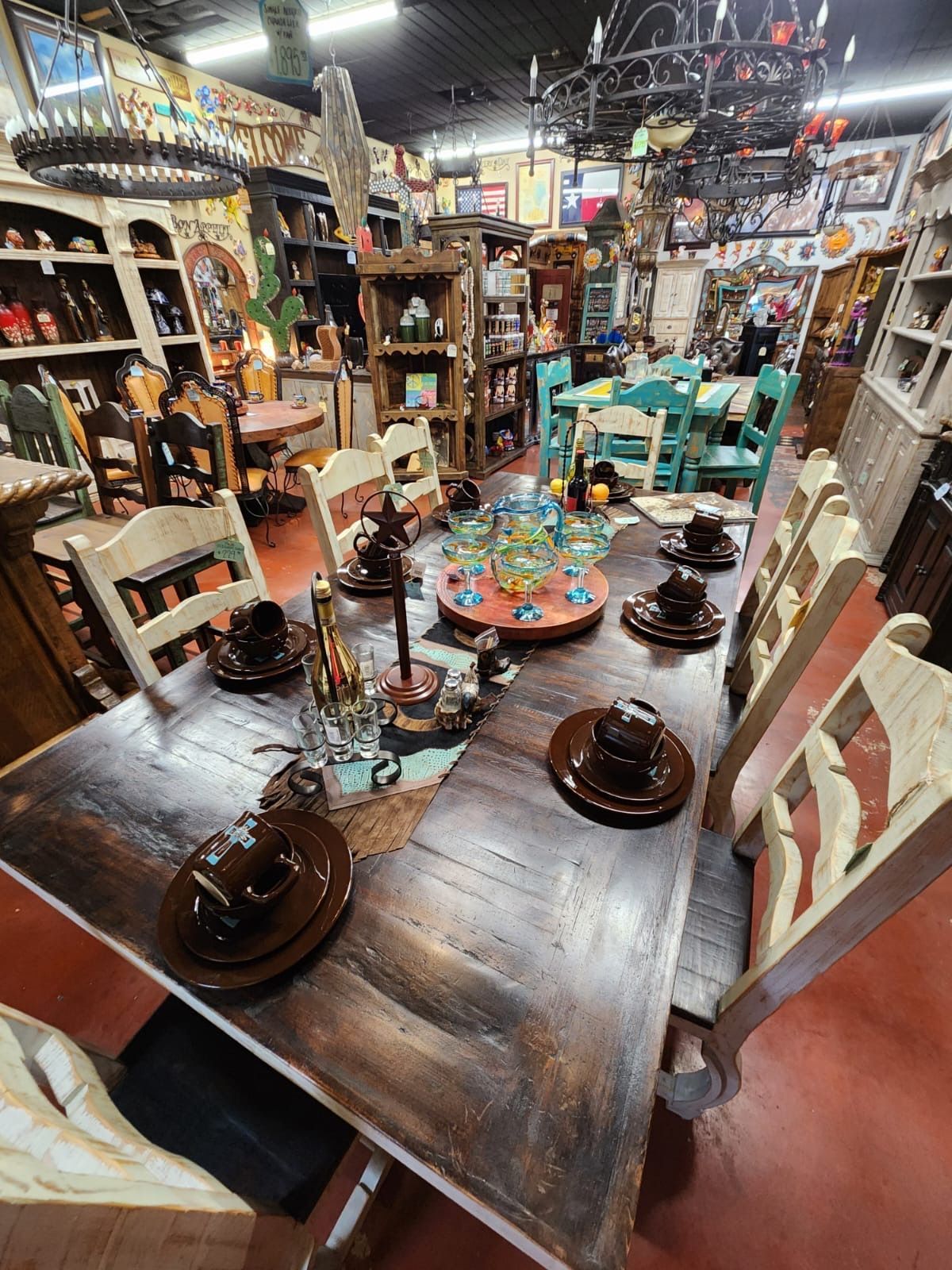 A dining table set with brown plates, chairs, and a colorful centerpiece inside a shop filled with furniture and decor.