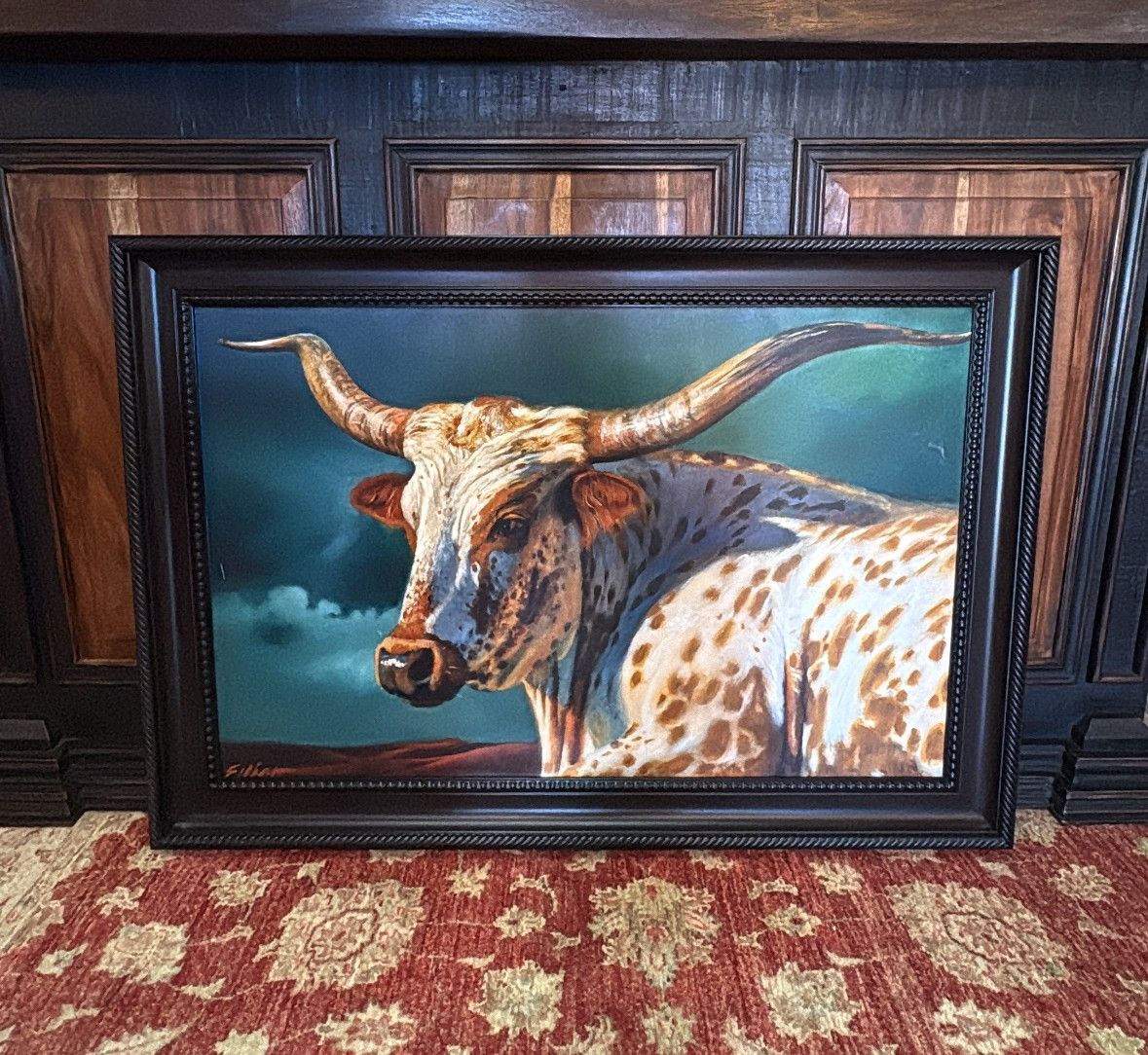 Painting of a longhorn steer with long horns and spotted coat, framed against a cloudy sky and red landscape.