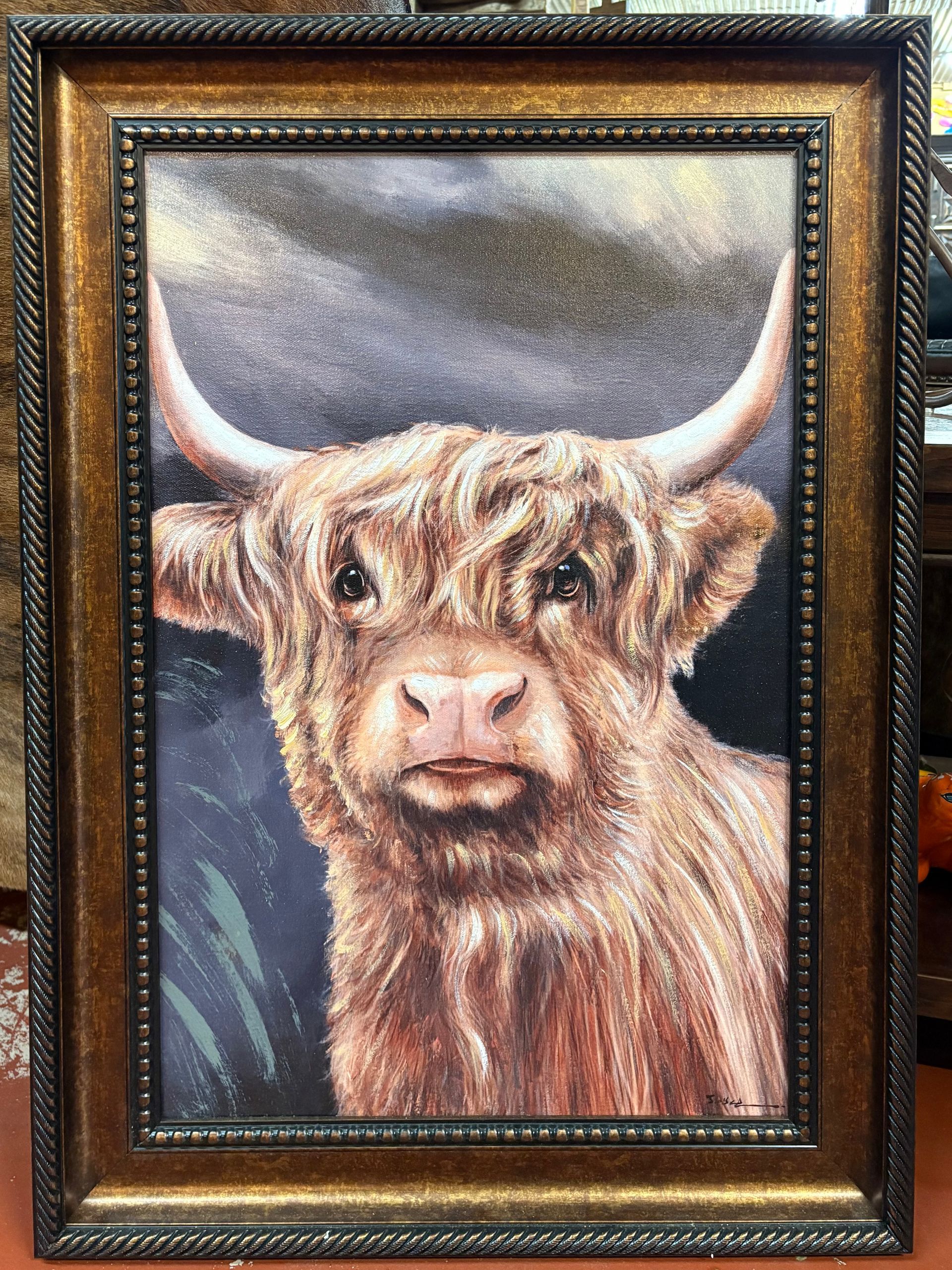 Framed portrait of a Highland cow with long, shaggy brown hair and large horns. It has a gentle expression.