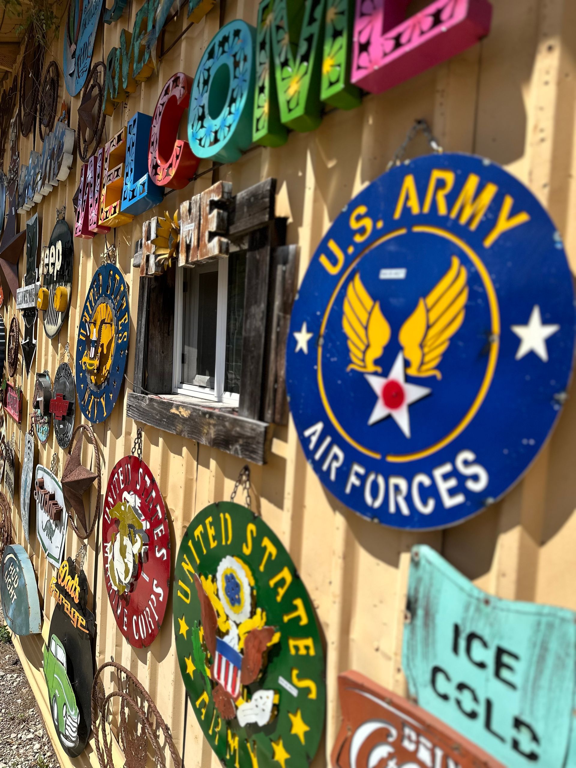 Wall display of colorful, weathered signs, including a U.S. Army Air Forces sign.