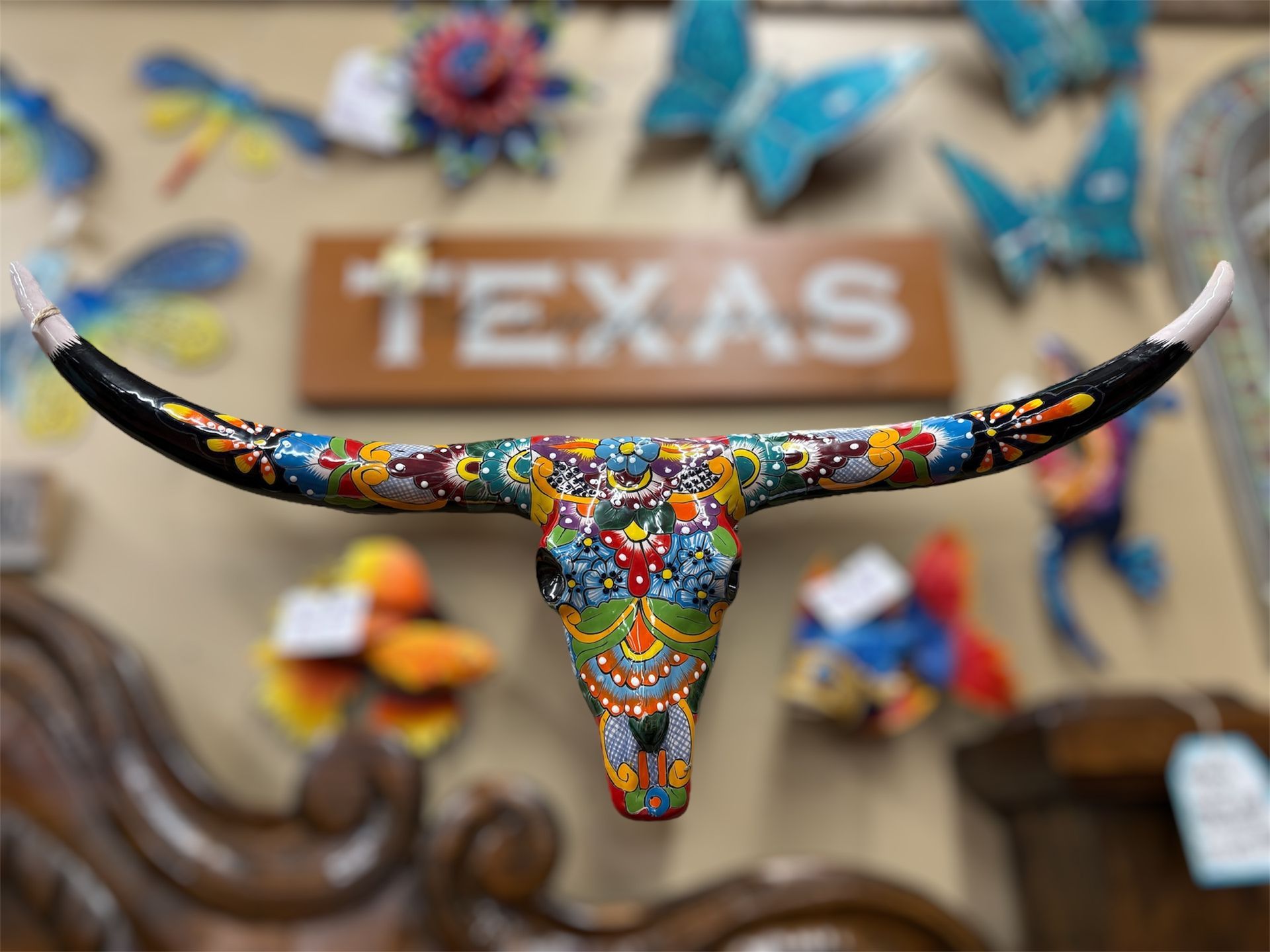 Colorful painted longhorn skull decor with TEXAS sign in background.
