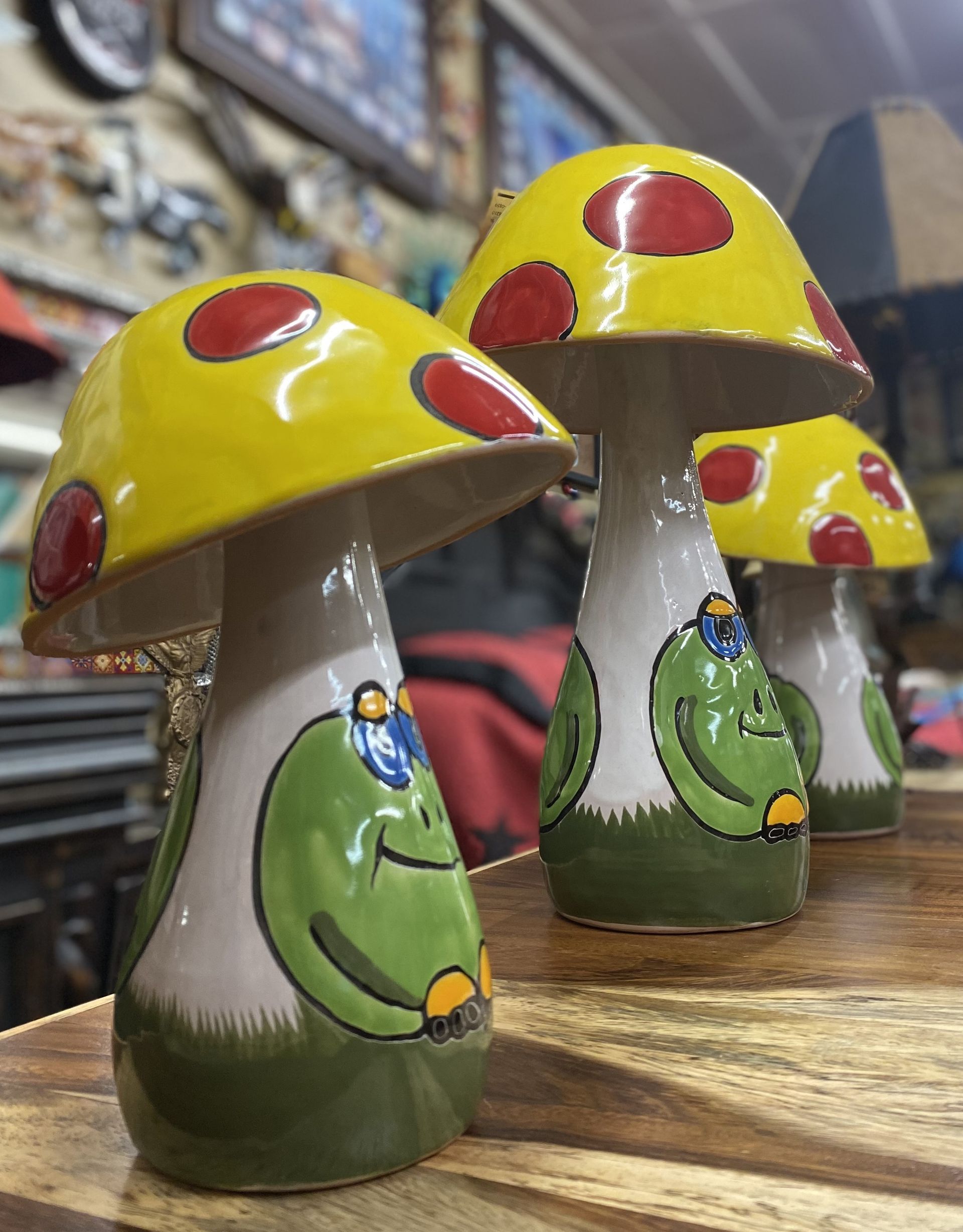 Three ceramic mushroom figurines with yellow caps and red spots, each featuring a smiling green frog.