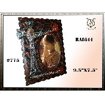 Ornate, dark wooden photo frame with a cross. The frame holds an oval photo of a girl praying.