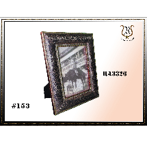 A decorative black framed photo with gold accents, tilted on a stand. The photo inside depicts dark figures.