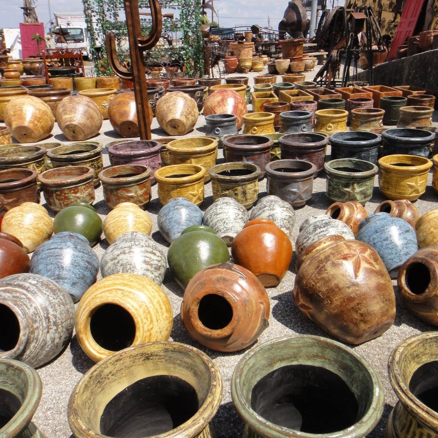 Rows of assorted ceramic pots for sale at an outdoor market, various colors and textures.