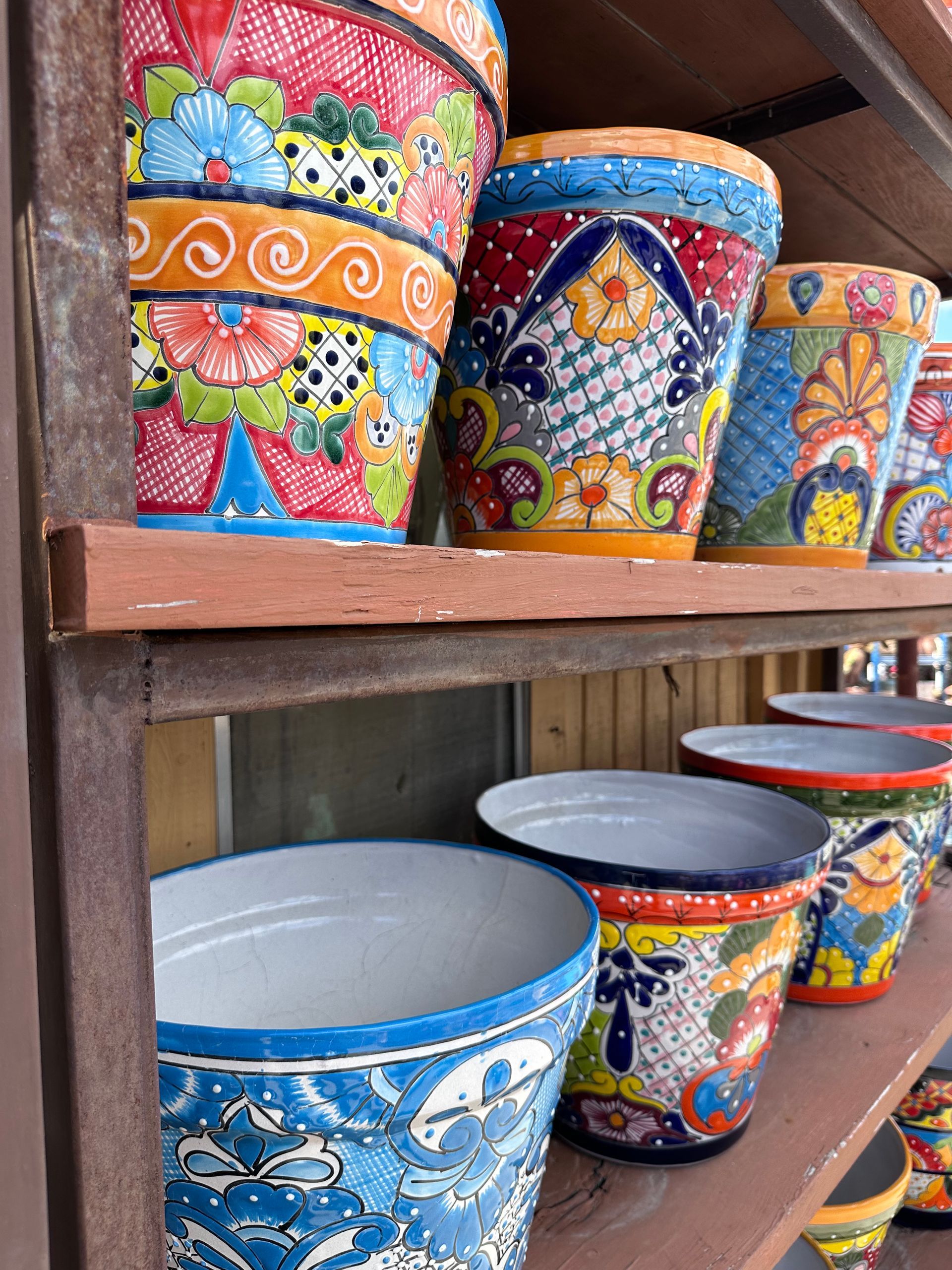 Colorful, ornate ceramic flower pots on shelves, with vibrant floral patterns and designs.