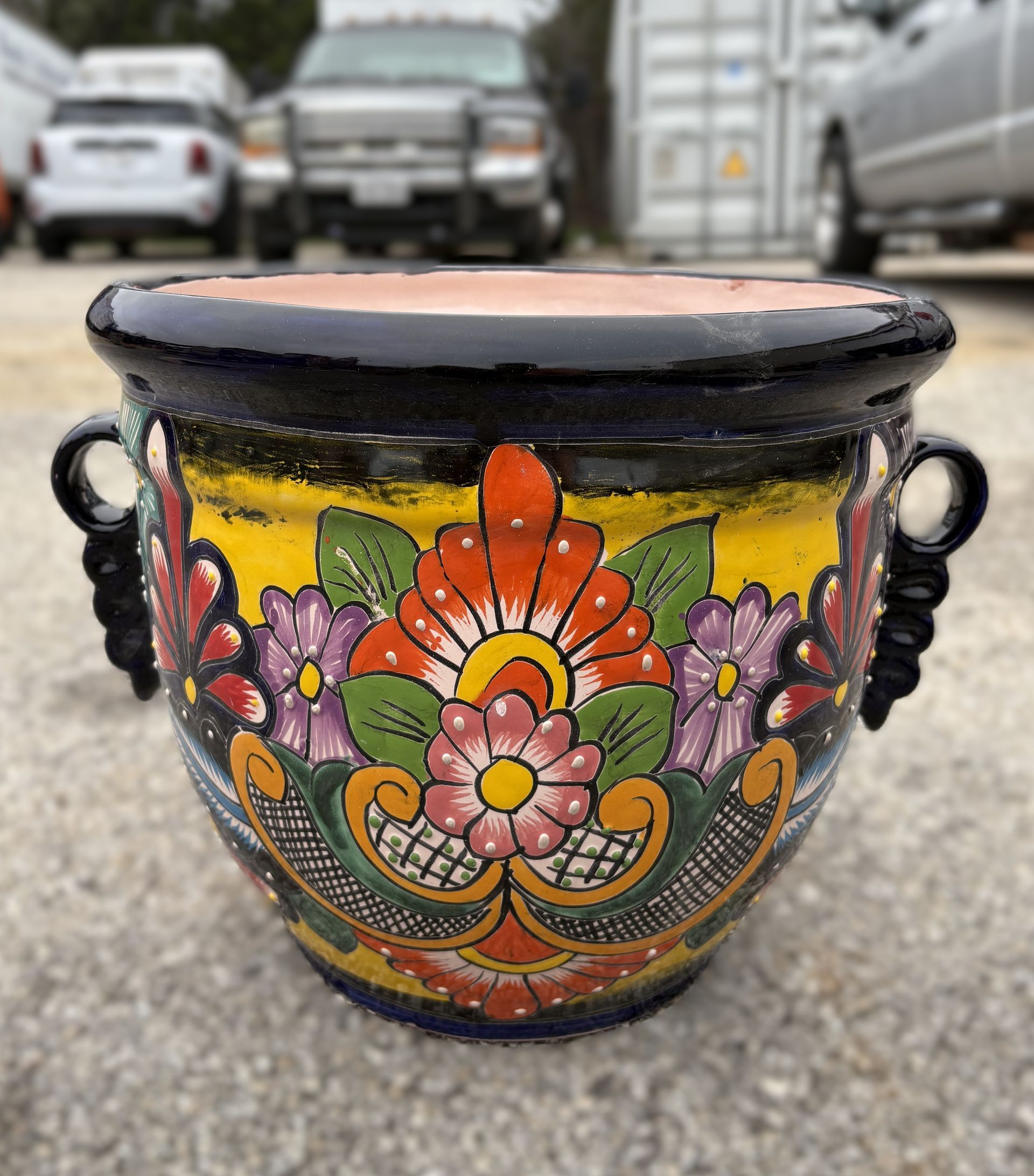 Colorful Talavera pottery bowl with floral design, black rim, and handles. Yellow, orange, purple, and green embellishments.