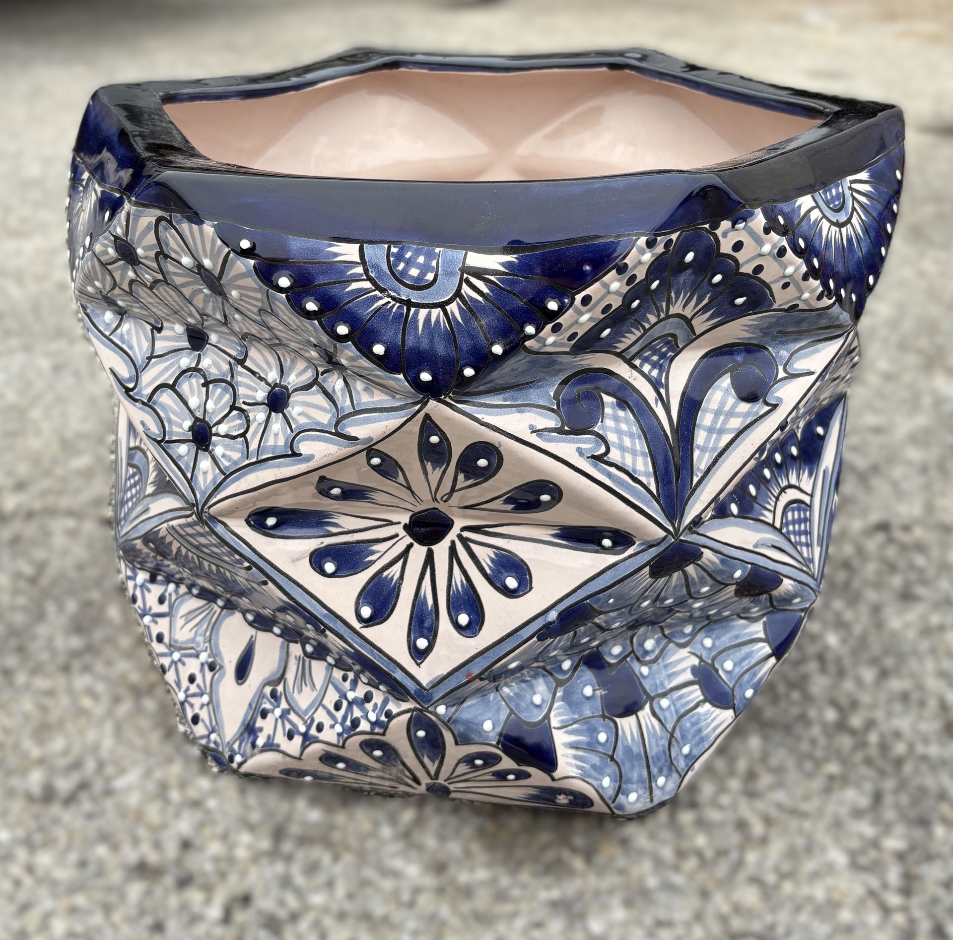 Blue and white patterned ceramic planter with a folded design, sitting on a concrete surface.