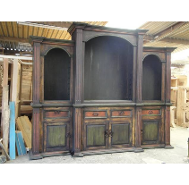 Wooden entertainment center with arched shelves and cabinets in a rustic, distressed finish; indoors.