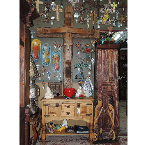 A display of religious artifacts, including crosses of various sizes and styles, an old wooden cabinet, and statues in a shop.