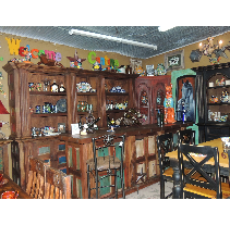 Interior of a rustic store with a wooden bar and shelves displaying colorful pottery and decor.