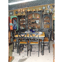 Dining room set with black cabinets and chairs, light brown tabletop, set against a tan wall with various decorative items.