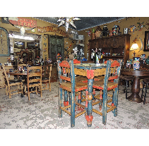 Restaurant interior with rustic wooden tables and chairs, eclectic decor on walls, and a star-shaped light fixture.