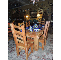 A wooden dining table and chairs set in a rustic-style room, set with blue and white China.