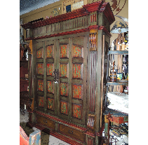 Large, ornate wooden cabinet with green and red accents, likely in a shop setting. It has multiple doors with detailed panels.