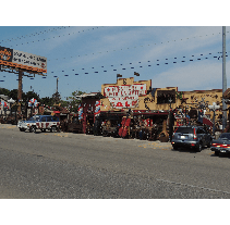 Street view of a vintage western-themed building with multiple cars parked out front, under a blue sky.