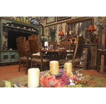 A dining room with a wooden table, chairs, and decorations. Candles and flowers are on the table, and artwork hangs on the walls.