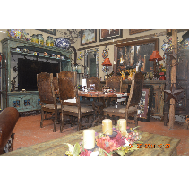A dining room with a rustic wooden table and chairs. The room is decorated with various ornaments, including an ornate cabinet and lamps.