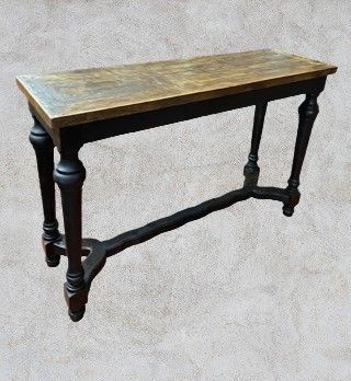Wooden console table with a light-brown top and black legs with ornate details.