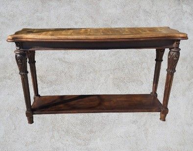 Wooden console table with a dark brown frame, a lower shelf, and decorative carved legs, against a textured gray background.