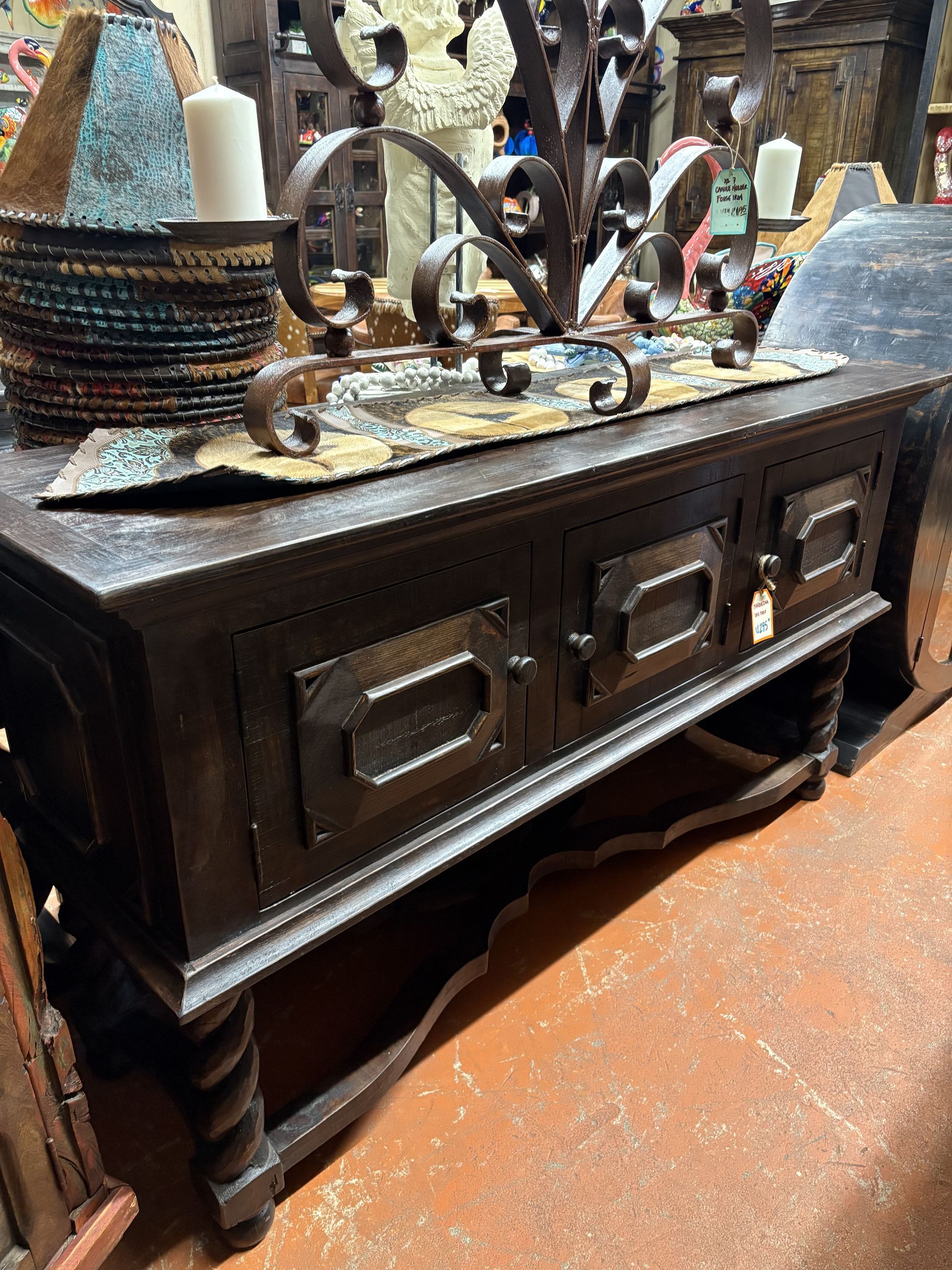 Dark brown, wooden cabinet with two doors and a shelf, decorated with metal accents and candles.