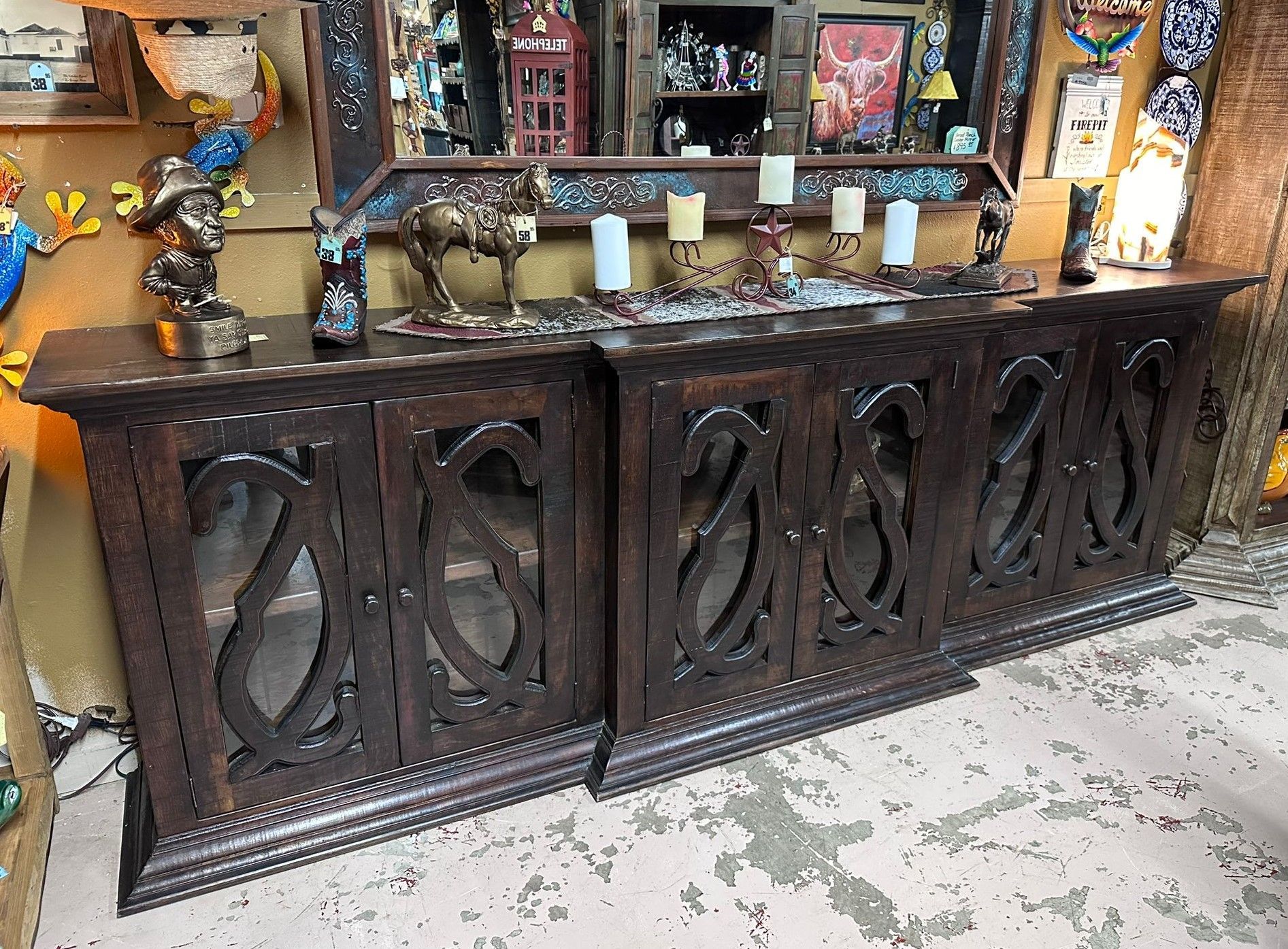 Dark wood buffet with carved doors, topped with candles and decorative objects. Set in a room with other eclectic furniture.