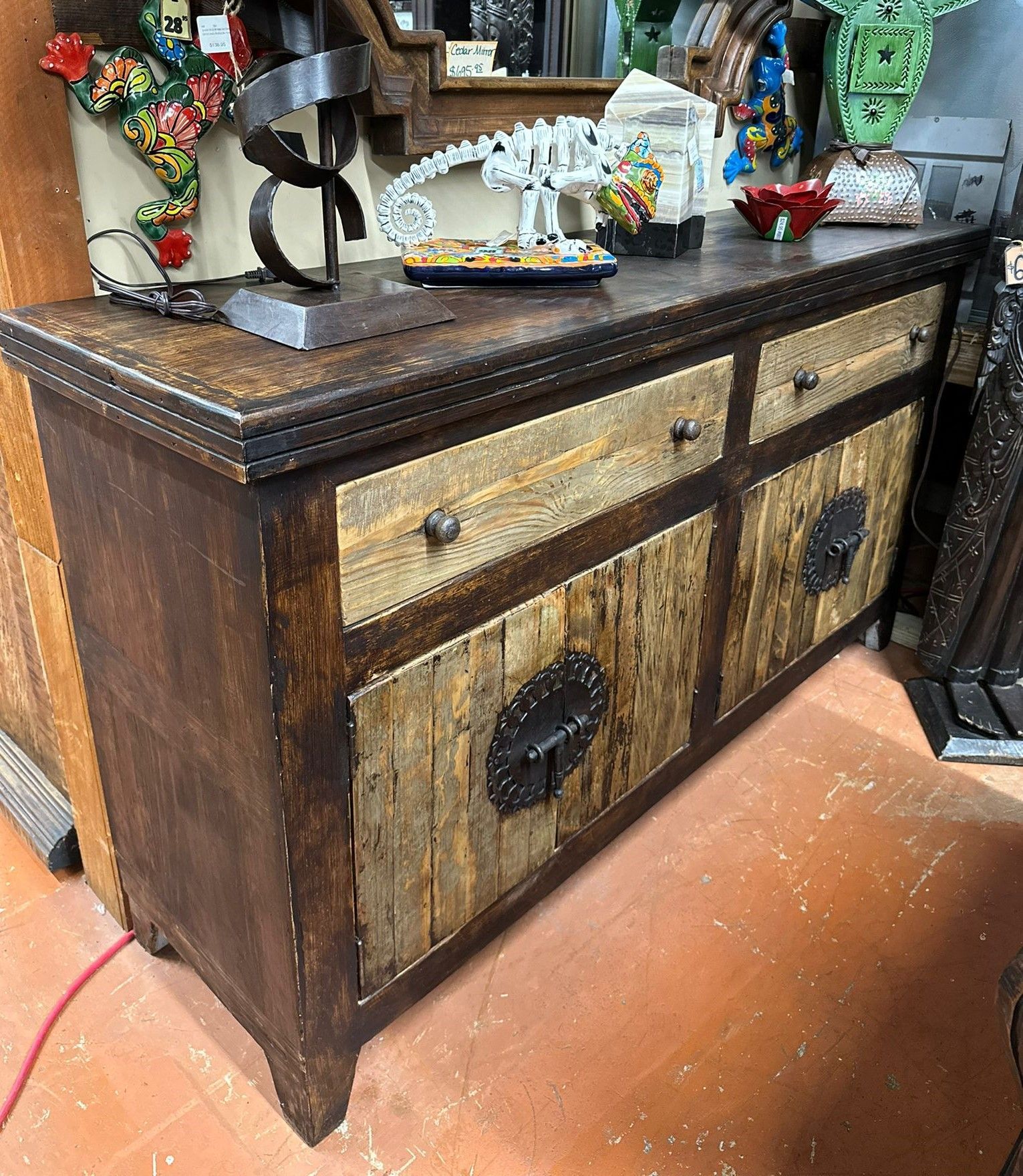 Rustic wooden cabinet with drawers and doors. Dark stained top and sides, light wood door panels with metal hardware.