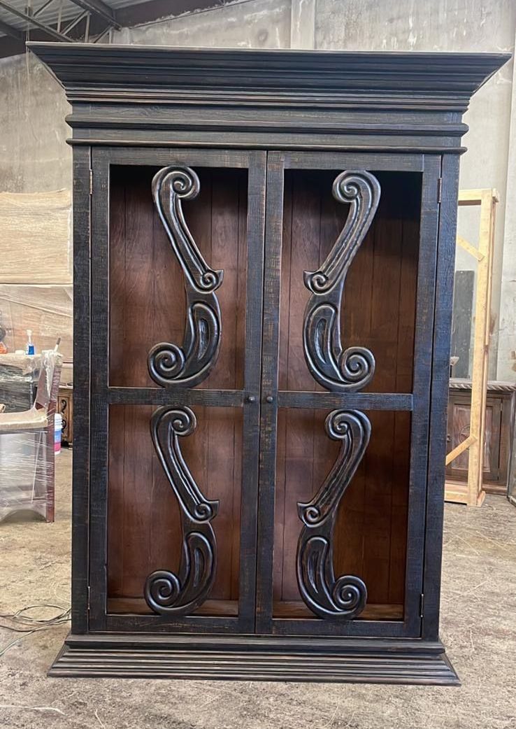 Black wooden cabinet with ornate scrolled details on the doors, set against a neutral background.