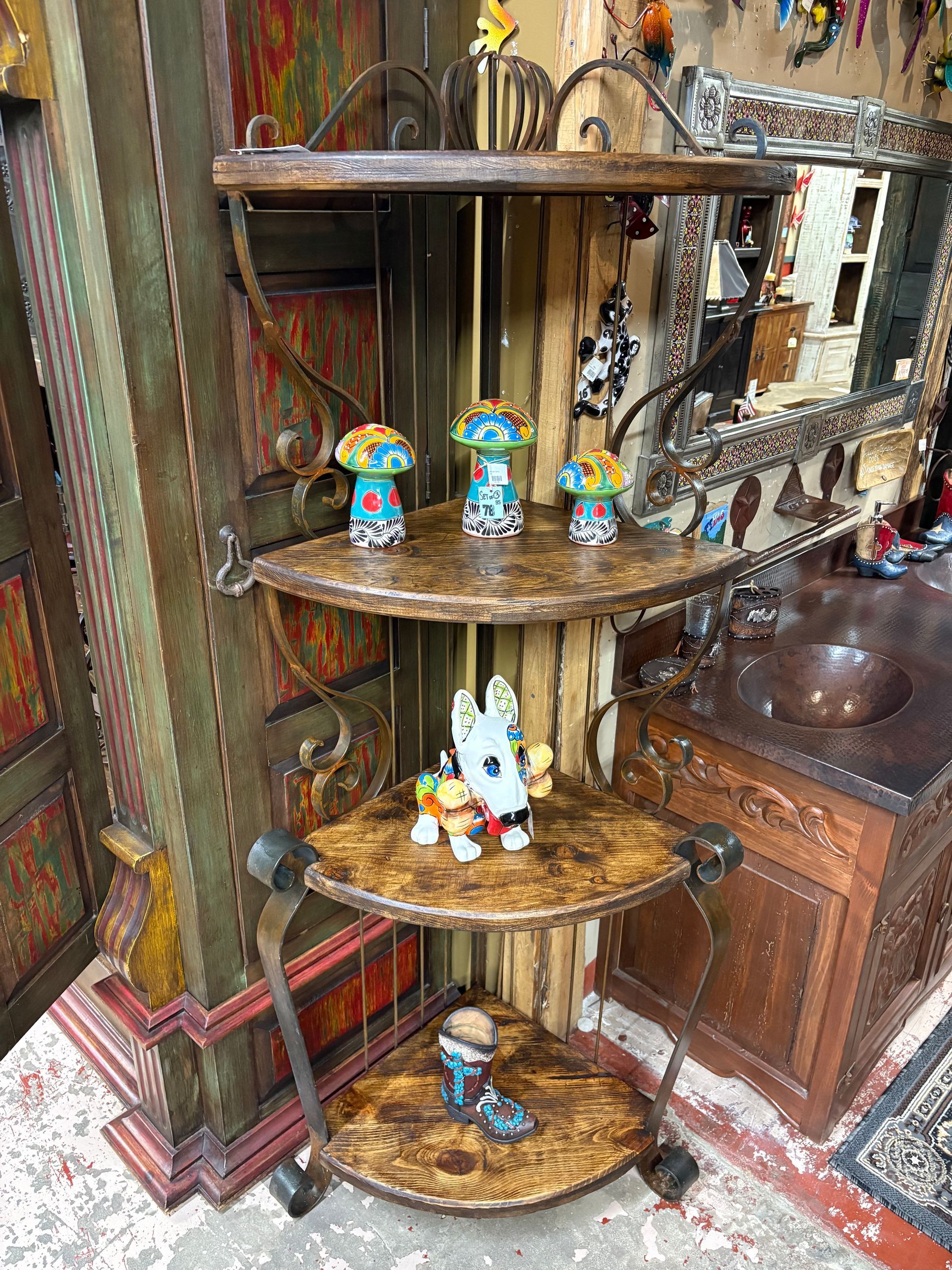 A multi-tiered corner shelf displays ceramic figurines: mushrooms and Bluey characters. The shelf has ornate metal supports and sits in a shop.