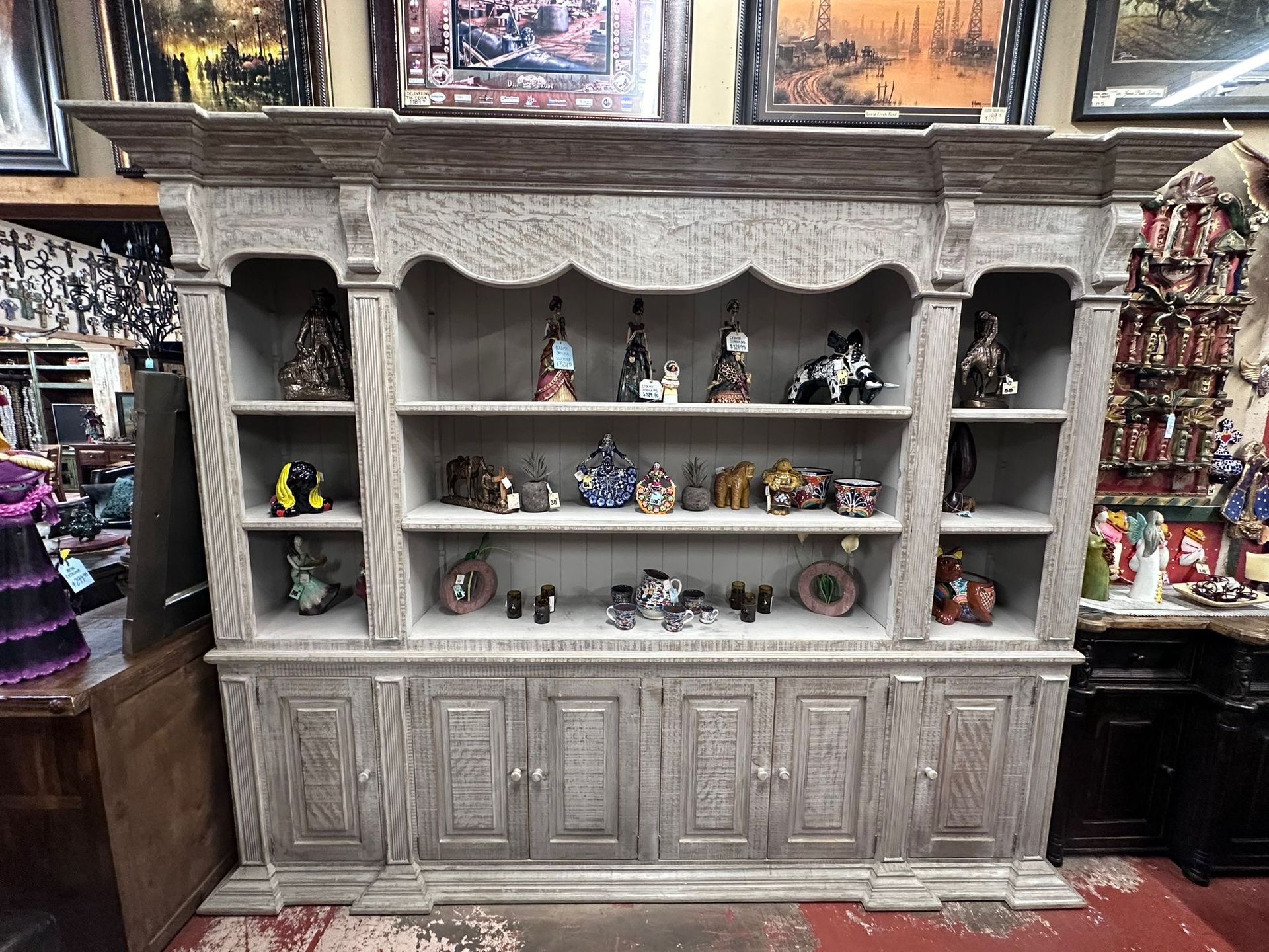 Large, light gray wooden cabinet filled with various figurines and decorations in a shop setting.