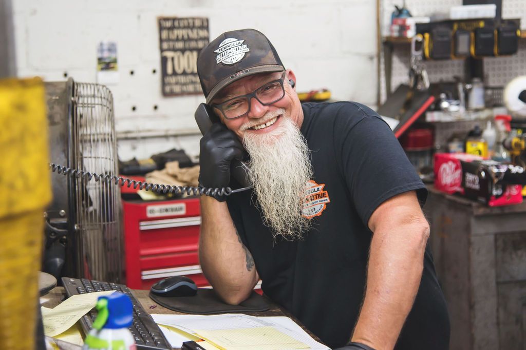 Smiling bearded man in a black cap leaning on a counter in a workshop-like store